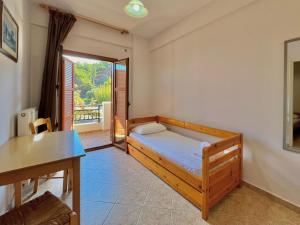 a bedroom with a bed and a table and a window at Marinos Studios and Apartments in Gialiskari