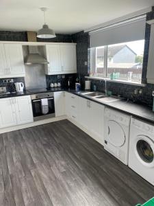 a kitchen with white cabinets and a washer and dryer at 31 end terrace. in Whitehead