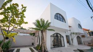 a white house with a palm tree in front of it at Miko Villa Seminyak in Seminyak