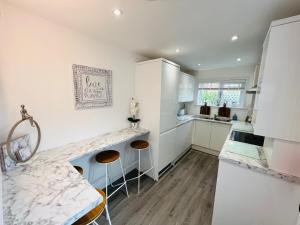 a kitchen with white cabinets and a marble counter top at Cosy Cottage in Stirling