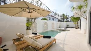 a patio with a pool and two chairs and an umbrella at Miko Villa Seminyak in Seminyak