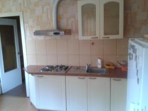 uma cozinha com armários brancos, um lavatório e um frigorífico em Ainaži em Ainaži