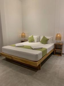 a bed with white sheets and green pillows on it at Summer Time Hiriketiya in Dickwella