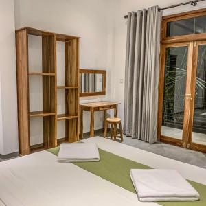 a bedroom with a bed and a table and a window at Summer Time Hiriketiya in Dickwella