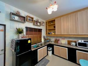 a kitchen with wooden cabinets and a black refrigerator at Baan Kulkandarin in Krabi +1 photo