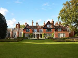 une grande maison en briques avec une pelouse devant elle dans l'établissement Macdonald Elmers Court Hotel, à Lymington