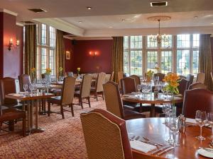 uma sala de jantar com mesas, cadeiras e janelas em Macdonald Elmers Court Hotel em Lymington