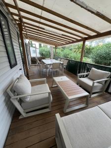 a deck with chairs and a table and a table and chairs at Camping Del Mar 265, Mobile Home Excellence, 3 chambres, 6 personnes, 2 Salles de Bain, bord de mer in Argelès-sur-Mer