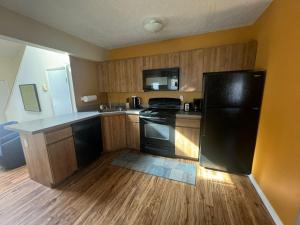 a kitchen with a black refrigerator and wooden cabinets at Cozy and quiet place to relax and unwind . in Tannersville