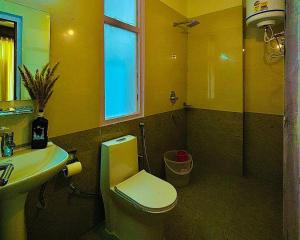 bagno giallo con servizi igienici e lavandino di The Ivy Mansion Sethan a Manāli