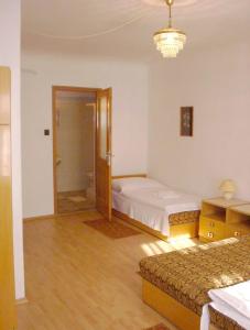 a bedroom with two beds and a door to a bathroom at Corvin Panzio in Győr
