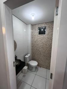a bathroom with a toilet and a television on the wall at Casa a 1 km andando até a praia, barra sul de Balneário Camboriú in Balneário Camboriú +6 photos