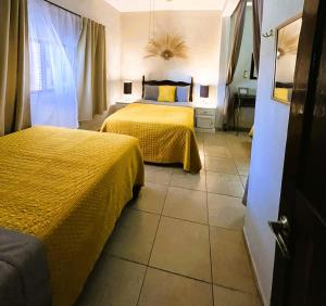 a bedroom with two beds with yellow comforters at Casa Punta Perula VILLAS in Pérula