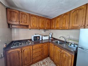 eine Küche mit Holzschränken, Spüle und Mikrowelle in der Unterkunft Casa Angelmar in Puerto de Santiago