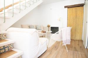 a white living room with white chairs and a staircase at El Granerillo de Cazalla in Cazalla de la Sierra