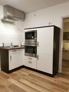 a kitchen with white cabinets and stainless steel appliances at 95qm Dachgeschoss für 1 bis 4 Personen - Alte Bäckerei - Neubaustandard in Bad Laasphe