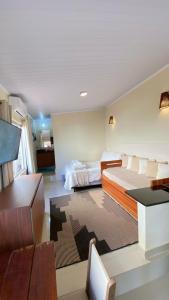 a room with two beds and a desk and a television at Chalé com ar condicionado e garagem in Alto Paraíso de Goiás