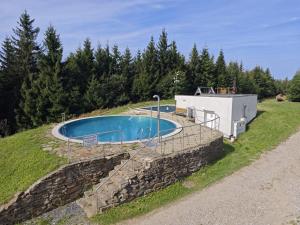 a swimming pool on a hill with a stone wall at Horská chata Severka in Dolní Lomná