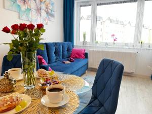 a living room with a table with food and a blue couch at A&R Apartamenty Wenedów III, bezpłatny prywatny parking in Koszalin