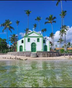 een wit gebouw op het strand met palmbomen bij RC FLAT Studio 05 Tamandaré, à 200m da praia in Tamandaré