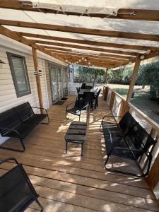 a wooden deck with chairs and tables and a pergola at Camping Del Mar B10, Mobile Home Excellence, 3 chambres, 6 personnes, bord de mer in Argelès-sur-Mer