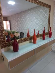 a row of red vases sitting on a shelf under a mirror at Casa em condomínio in Cuiabá