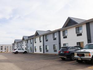 a large white building with cars parked in a parking lot at Travelodge by Wyndham Rapid City - Black Hills in Rapid City