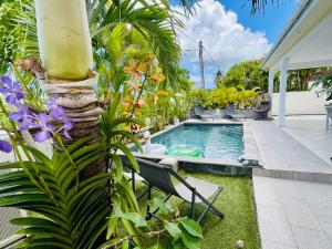 a swimming pool in a yard with plants at Villas TROPICAL & EXOTIC, 6 chambres avec 2 piscines in Le Moule