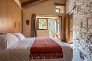 a bedroom with a large bed with a stone wall at Fogar Mozárabe in Peñalba de Santiago +22 photos