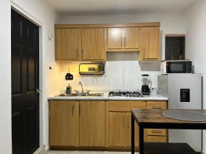 Una cocina con gabinetes de madera y un refrigerador blanco. en Cómodo Estudio en la Kennedy cerca de Consulado, en Nogales