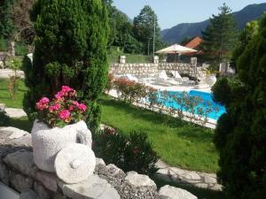a stone retaining wall with flowers and a swimming pool at Villa Kamena in Kotor