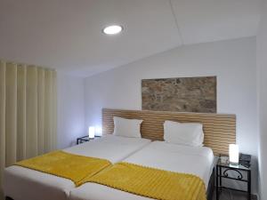 Un dormitorio con una cama grande con sábanas blancas y manta amarilla. en Largo da Fonte, en Sertã 39 fotos más