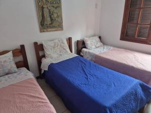 a bedroom with two beds and a blue blanket at Charmosa casa com piscina em Búzios in Búzios +19 photos