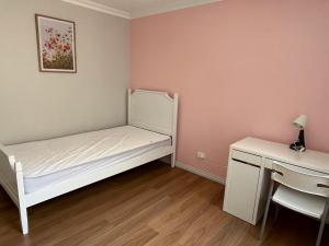 a small bedroom with a white bed and a desk at Cindy garden in Perth