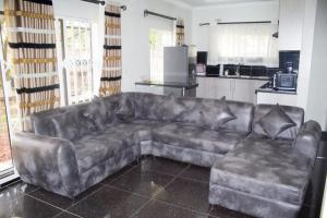 a leather couch in a living room with a kitchen at Amazing Guest House in Harare
