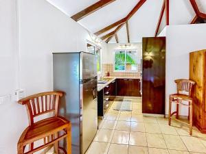 a kitchen with a refrigerator and two wooden chairs at O'coco Bungalow- Breathtaking waterfront views, endless memories in Paea