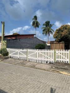 a white fence in front of a house with palm trees at Chalé Park Mar, São José e Maragogi in São José da Coroa Grande