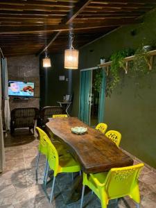 ein Esszimmer mit einem Holztisch und gelben Stühlen in der Unterkunft Chalé Park Mar, São José e Maragogi in São José da Coroa Grande + 38 Fotos