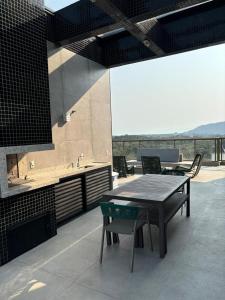 a patio with a table and chairs and a kitchen at Apto Elegante com Localização Privilegiada e Rooftop incrível in Florianópolis