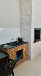 a kitchen with a sink and a brick fireplace at Casa próxima aos pontos turísticos in Foz do Iguaçu
