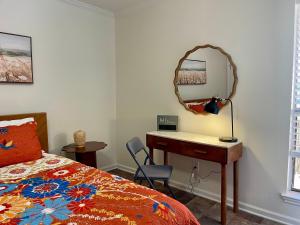 ein Schlafzimmer mit einem Schreibtisch, einem Bett und einem Spiegel in der Unterkunft Cozy Condo in Lake Charles