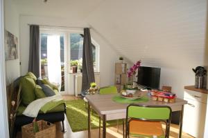a living room with a table and green chairs at Haus am See in Einruhr