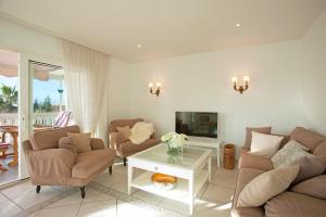 Villa Costa Del Sol في مربلة: غرفة معيشة مع أريكة وكراسي وتلفزيون