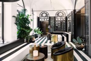 un hall avec des chaises noires, des tables et des plantes dans l'établissement Senato Hotel Milano, à Milan