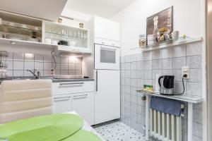 a small kitchen with white cabinets and a refrigerator at Apartments Neuss in Neuss +32 photos