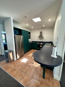 a kitchen with a black table and a refrigerator at 2 Room Luxury Beach Escape 112sq Mt Maunganui in Mount Maunganui +27 photos