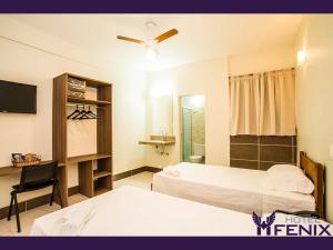 Habitación de hotel con 2 camas y TV en Hotel Fenix, en Assis