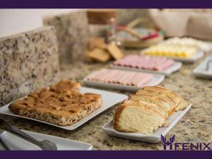 stół z kilkoma kawałkami chleba i wypieków na talerzach w obiekcie Hotel Fenix w mieście Assis