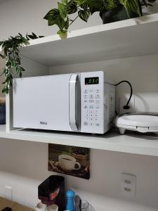 un microondas blanco en un estante con una planta en Flat Lux - com Piscina e Netflix, en Río de Janeiro