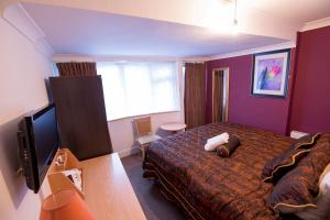 a hotel room with a bed and a flat screen tv at Citybest Hotel in Ilford